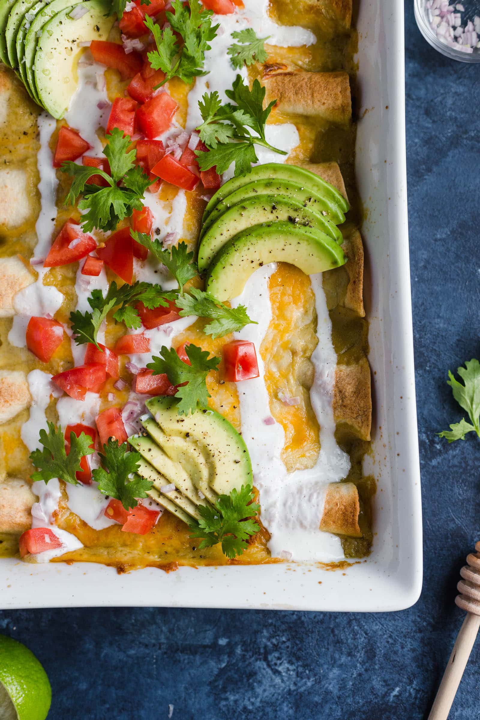 Honey Lime Chicken Enchiladas topped with avocado, tomatoes, and sour cream