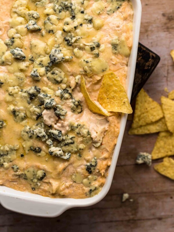 beer cheese buffalo chicken dip in a serving dish with a chip