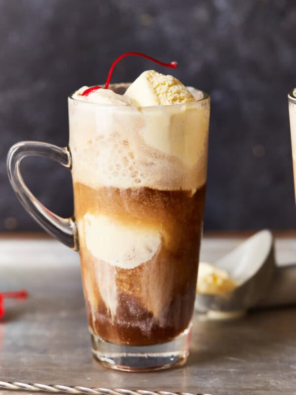 an alcoholic root beer float in a clear glass with a handle.