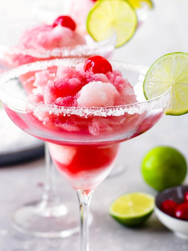 cherry limeade margarita in a margarita glass with a lime on the rim