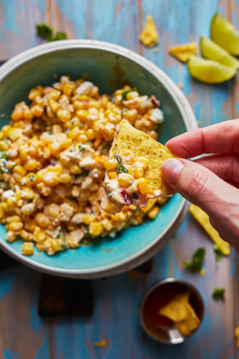 dipping chip into bowl of healthy mexican street corn dip