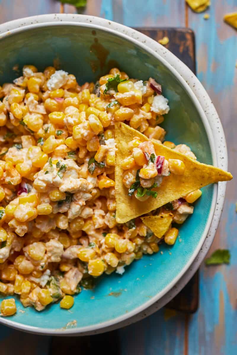 dipping chip into bowl of healthy mexican street corn dip