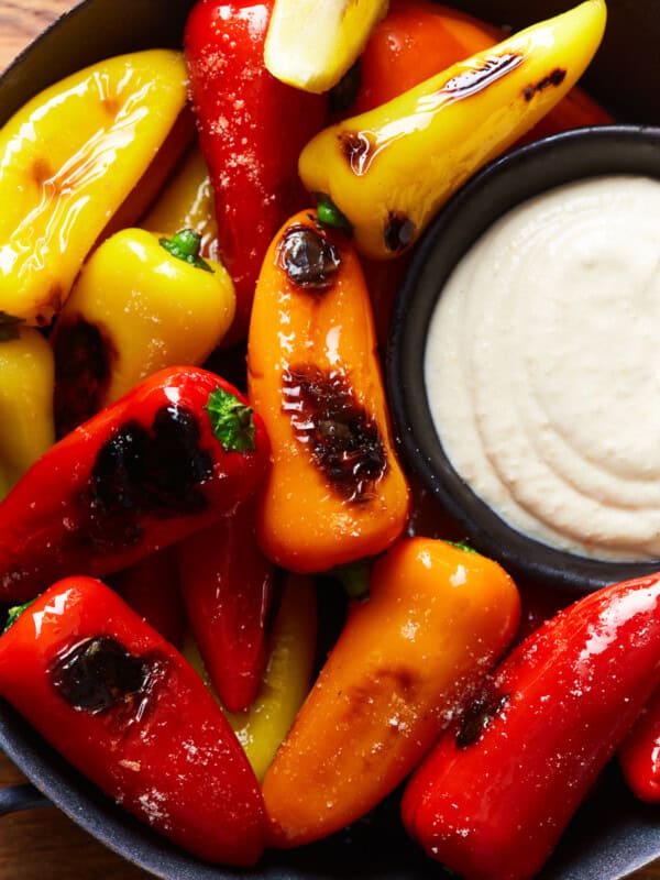 overhead view of tricolor blistered sweet peppers in a black bowl with goat cheese dip.