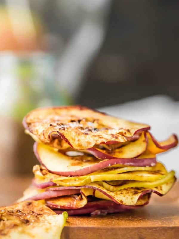 A stack of apple slices on a cutting board for making microwave apple chips.