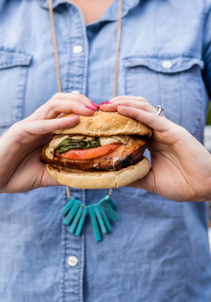 femme tenant un sandwich au poulet Caprese