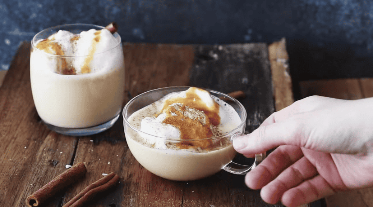 salted caramel eggnog in a glass with egg whites and caramel sauce on top.