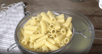 cooked rigatoni pasta in a strainer.