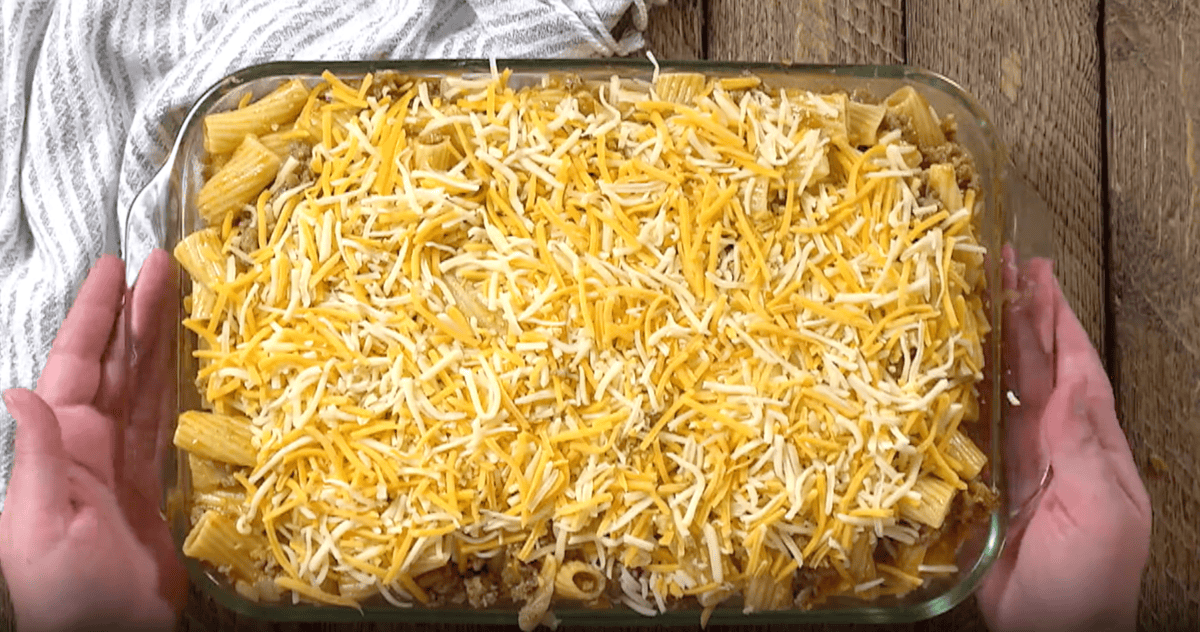 mexican mac and cheese topped with shredded cheese in a casserole dish.