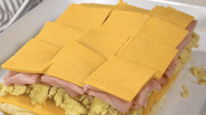 bottom slider rolls layered with cheese, eggs, ham, and more cheese.