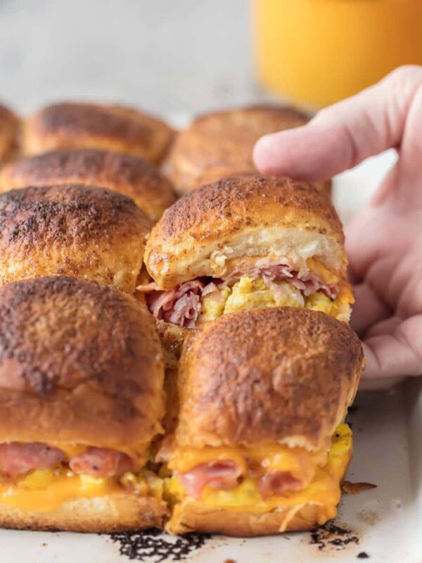 These CHEESY BAKED BREAKFAST SLIDERS are so easy and perfect for feeding a crowd! Baked on Hawaiian rolls with layers of ham, egg, and cheese and topped with a brown sugar dijon butter sauce! TOO GOOD!