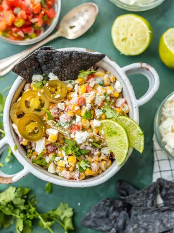 This MEXICAN STREET CORN SALSA recipe is my favorite spicy corn dip, just perfect for every occasion! Roasted corn, feta, lime juice, sour cream, cilantro, pico de gallo, and more!