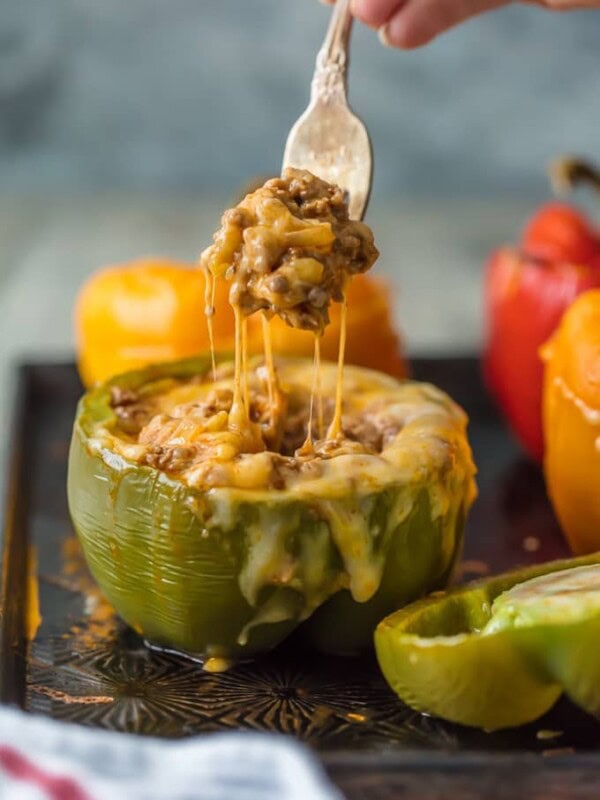 This STUFFED PEPPERS RECIPE is our go-to easy dinner recipe. These Cheesy Enchilada Stuffed Peppers are loaded with beef, green chiles, onions, enchilada sauce, and so much cheese! You won't believe how easy these are and how much your entire family will love them. 