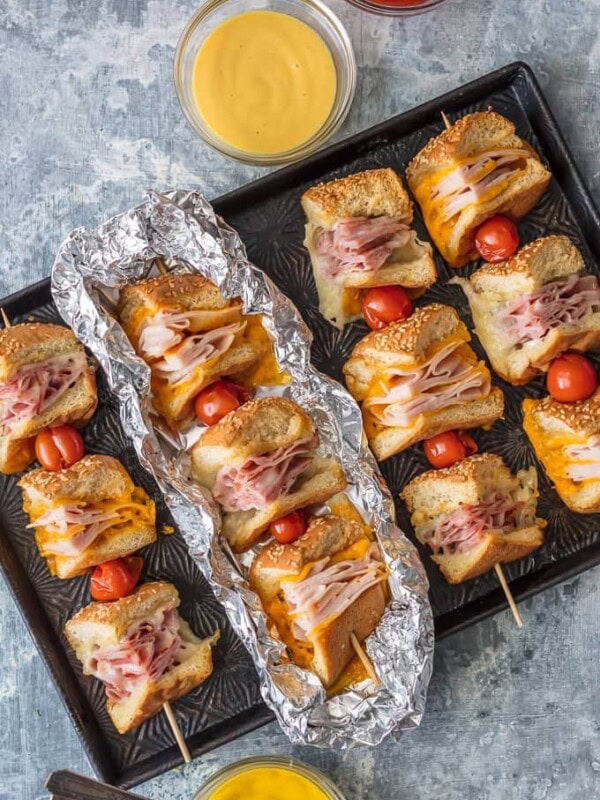 These Cheesy Garlic Butter Sandwich Skewers are a twist on an old classic. Cheesy Ham, Turkey, and Roast Beef sandwiches drizzled with garlic butter and cooked to perfection in foil packets; such a fun and delicious lunch or dinner!