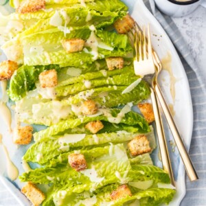 a bed of lettuce with croutons, cheese, and caesar dressing