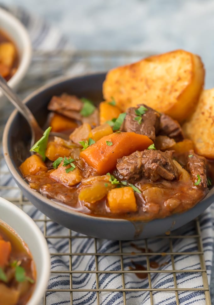 a bowl of beef stew with carrots and bread