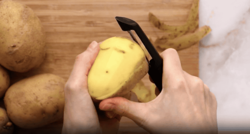 peeling potatoes with a potato peeler.