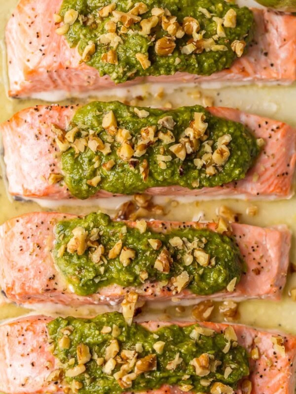 This Baked Pesto Salmon recipe is our favorite simple yet elegant seafood dinner. This Baked Salmon Recipe with Basil Walnut Pesto is bursting with flavor and good fat. The tender flaky salmon is basted in butter, white wine, and lemon juice before baking and then topped with an amazing nutty and rich Basil Walnut Pesto. Best Baked Salmon Recipe ever!