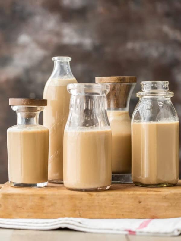 Four jars of homemade Bailey's Irish cream on a wooden cutting board.