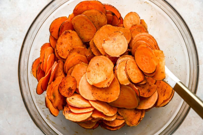 sliced sweet potatoes in a bowl with a rubber spatula.