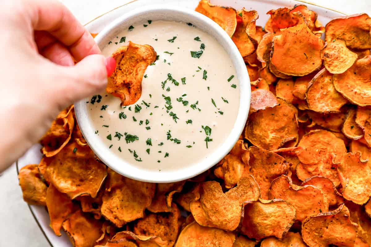 dipping a baked sweet potato chip into dip.