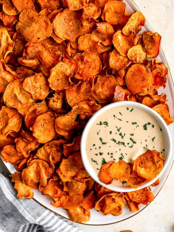 overhead view of baked sweet potato chips on a platter with dipping sauce.