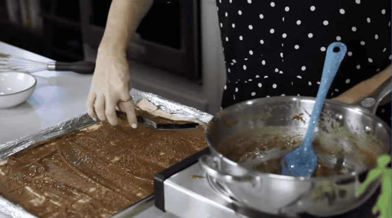 spreading caramel over saltine crackers with an offset spatula.