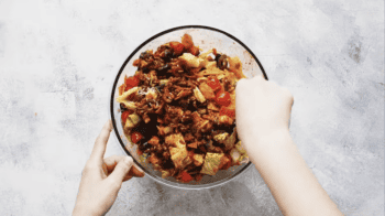tossing taco salad in a glass bowl.