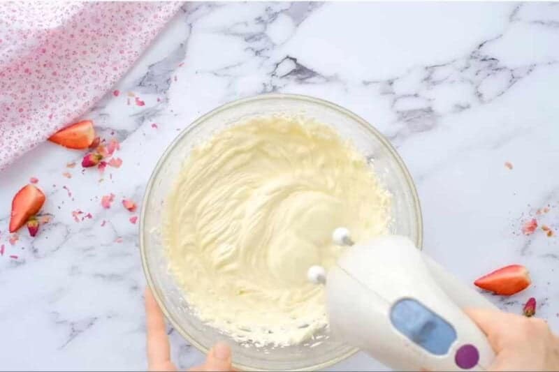 preparing cream cheese frosting in a glass bowl