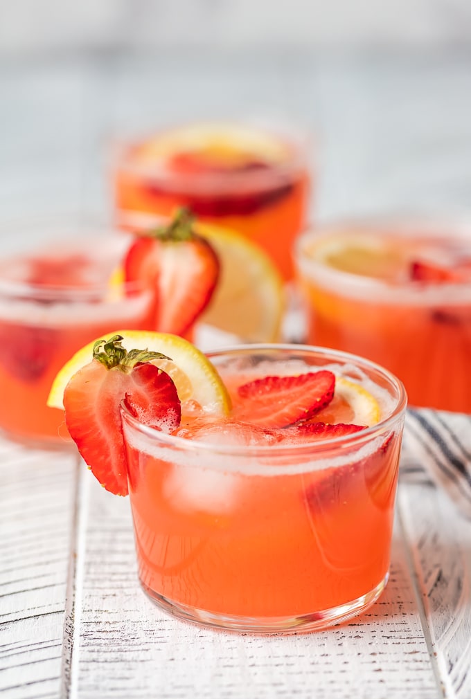 Glasses of strawberry lemonade punch garnished with fresh slices of lemon and strawberries