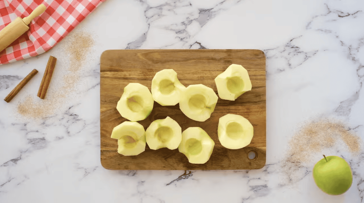 peeled, cored, and halved apples on a cutting board.