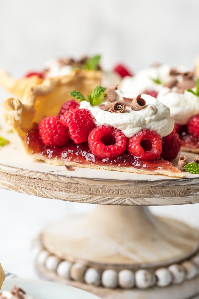 Raspberry tart topped with whipped cream, chocolate shavings, and mint