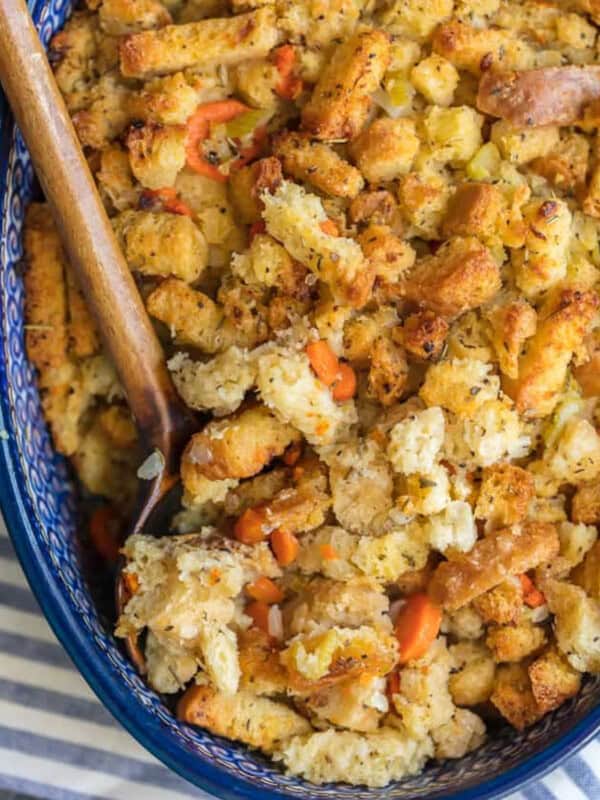 Homemade turkey stuffing in a blue dish with a wooden spoon.