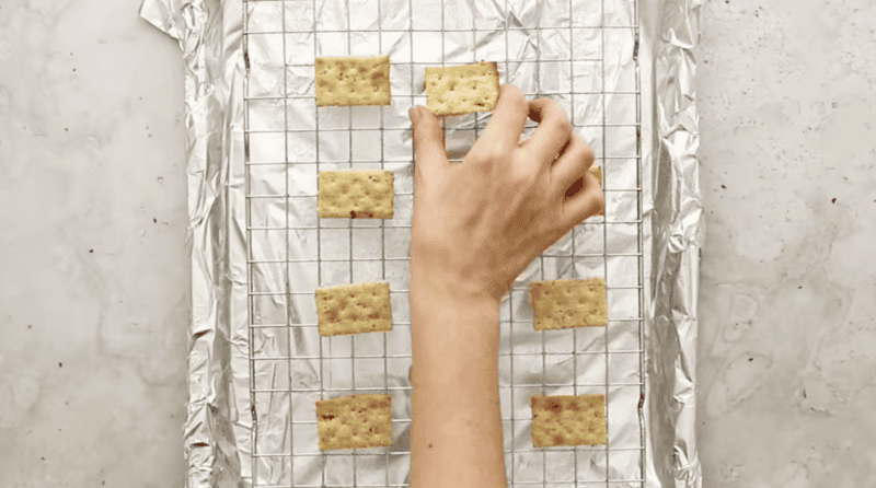 placing crackers on a wire rack set in a baking sheet.