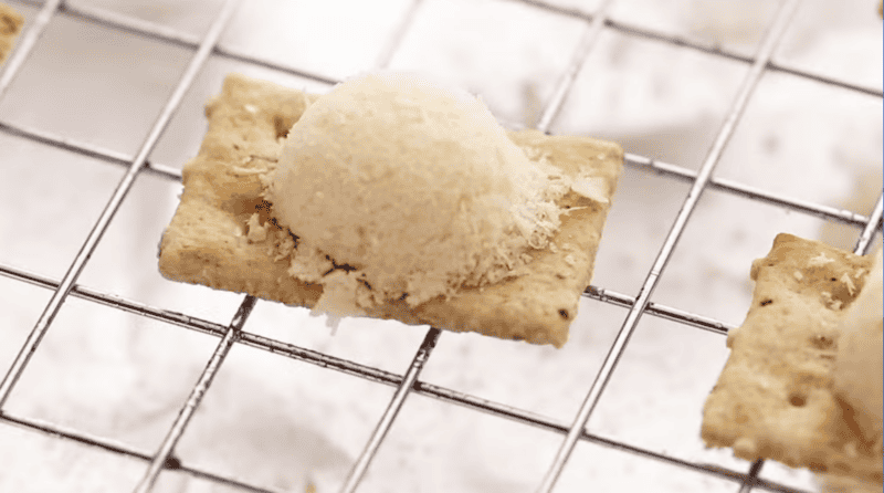 a teaspoon-sized mount of grated Parmesan on top of a cracker on a wire rack.