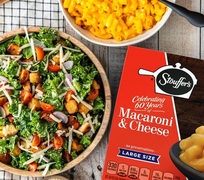 kale salad in a bowl next to a box and bowl of stouffer's macaroni and cheese