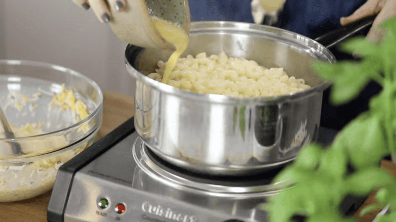 pouring melted butter over noodles in a pot.