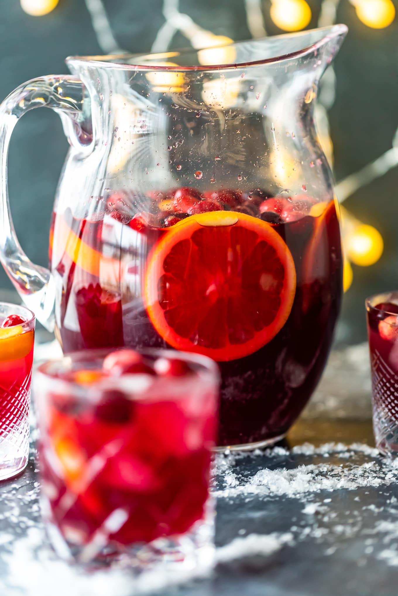 orange cranberry sangria in a pitcher, surrounded by glasses of sangria