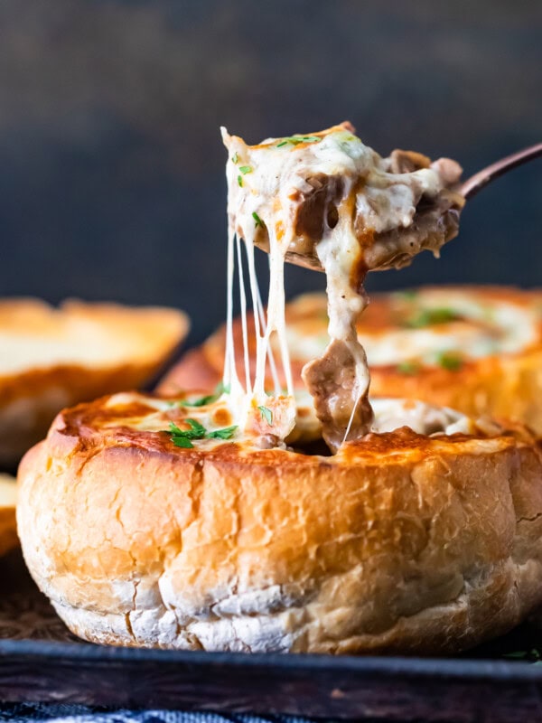 A close up of cheesy soup in breadbowl