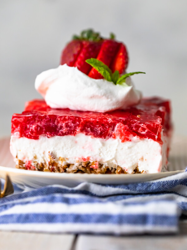 Strawberry Pretzel Salad on a plate with whipped cream and strawberries on top