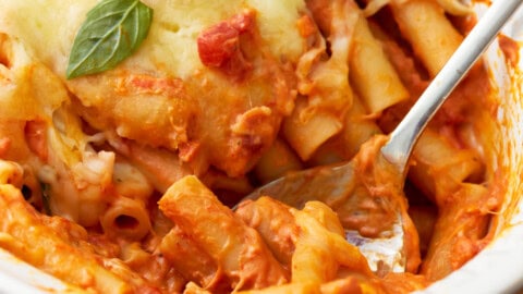 close up of baked ziti in a baking dish with a spoon.