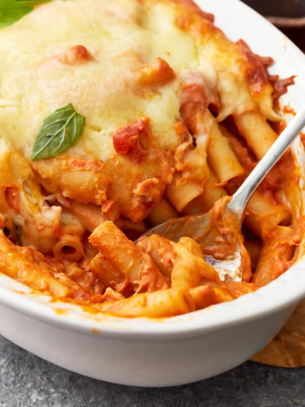 close up of baked ziti in a baking dish with a spoon.