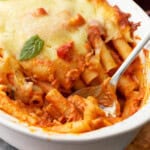 close up of baked ziti in a baking dish with a spoon.