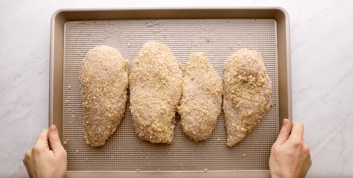 4 panko-breaded chicken breasts on a baking sheet.