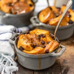 A dish of apple bread pudding with raisins on a wooden board, accompanied by a refreshing St. Patrick's Day punch.