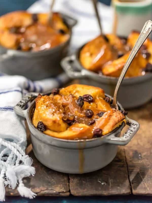 A dish of apple bread pudding with raisins on a wooden board, accompanied by a refreshing St. Patrick's Day punch.