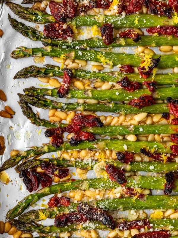 Oven Roasted Asparagus with sun dried tomatoes, pine nuts, garlic, and more is a delicious Mediterranean-inspired side dish fit for any occasion. This easy roasted asparagus recipe is quick to make yet filled with flavor! Add this asparagus side dish to your holiday meals, or just to your weeknight dinners. Either way, it's sure to be a hit!