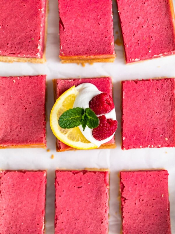 Raspberry Bars are a delicious and easy dessert to serve for any holiday, party, or summer afternoon. These fruity Raspberry Lemon Bars have the perfect flavor, the perfect texture, and the perfect pink color. Top them with some fresh fruit, powdered sugar, and whipped cream for a delightful treat!