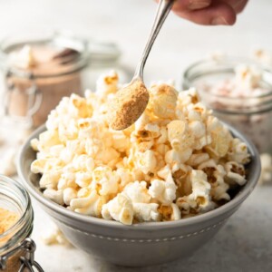 popcorn salt on a spoon above a bowl of popcorn