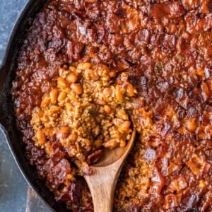 a spoon scooping baked beans out of a skillet