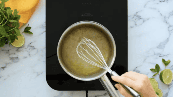 boiling lime simple syrup in a saucepan with a whisk.